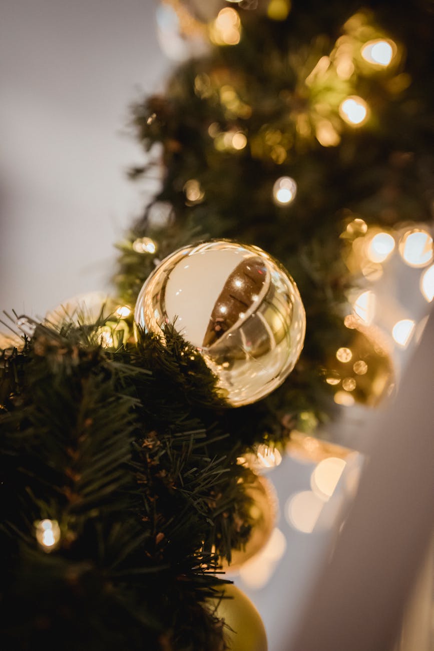 christmas golden ornament on artificial coniferous garland with lights