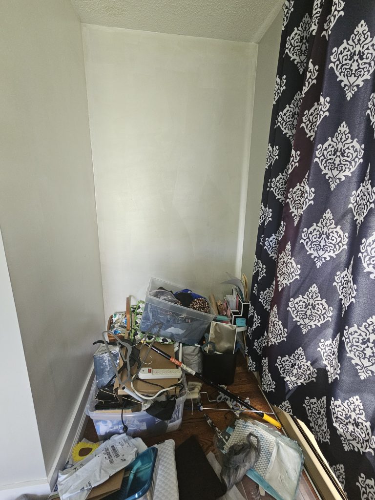 Corner of room with unfinished walls and junk in the floor